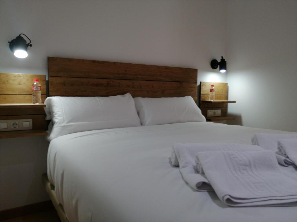 a bedroom with a large bed with white sheets and pillows at Hostal Cuéntame Evolución Auto Check in in Burgos