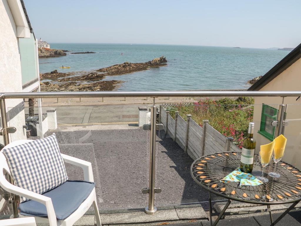 een balkon met een tafel en een stoel en de oceaan bij Min Y Traeth in Amlwch