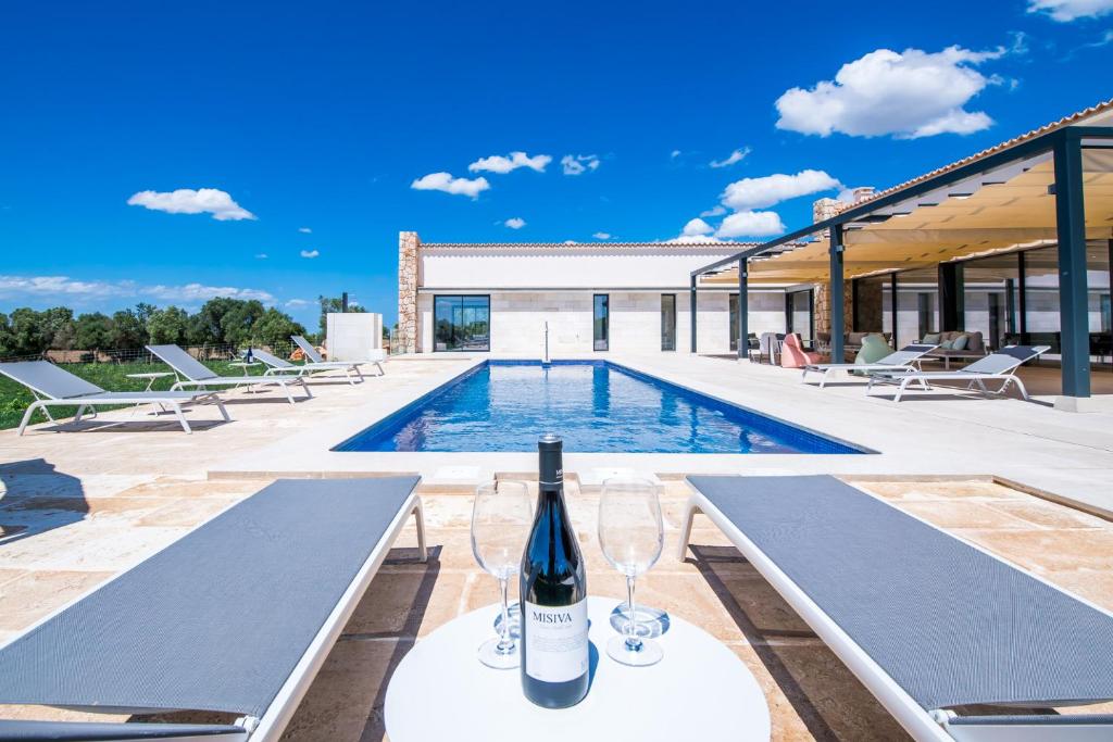 een villa met een zwembad en een fles wijn bij Pura Vida in Ariany