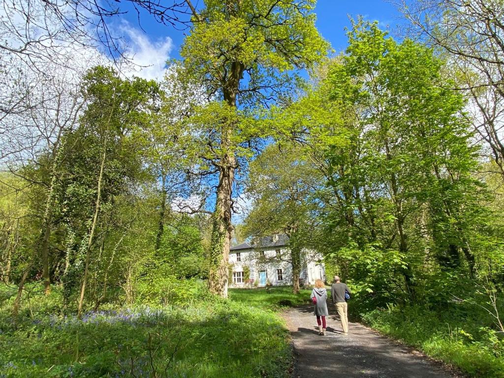 two people walking down a dirt road in front of a house at Blackhill Woods Retreat in Abbeyleix