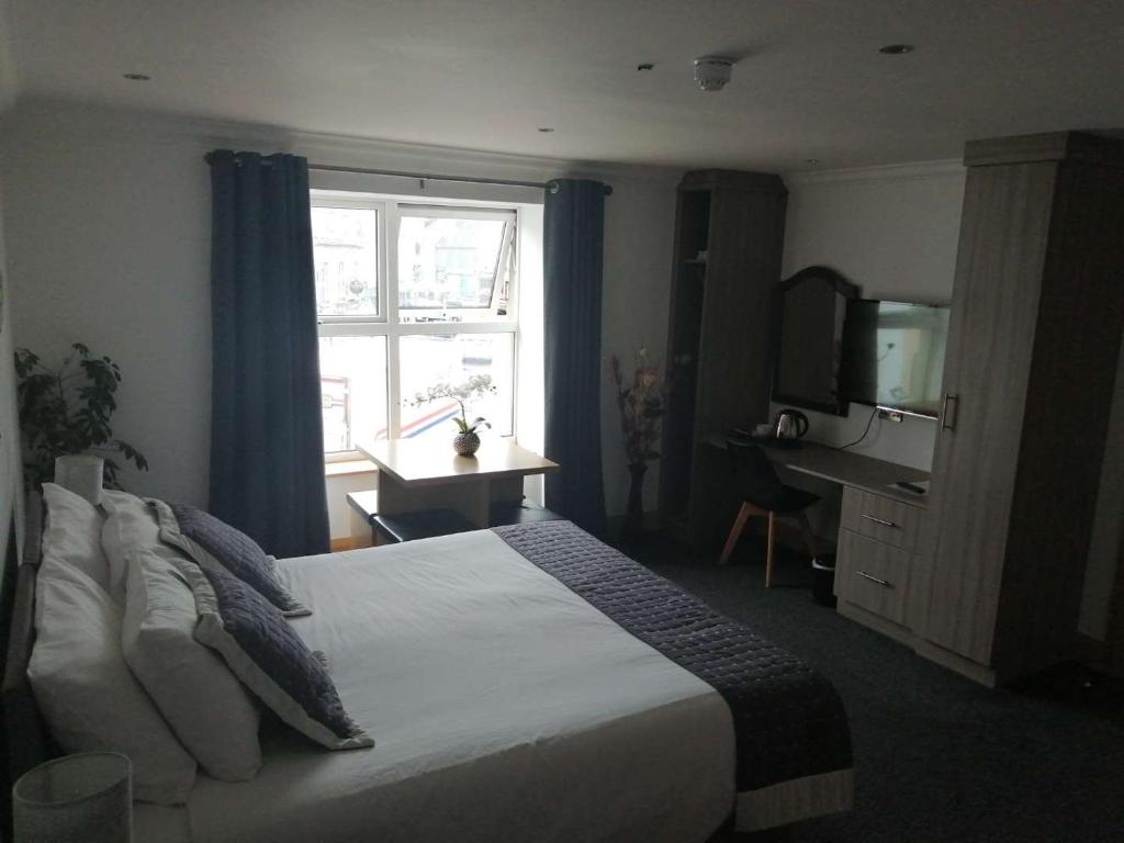 a bedroom with a bed with a television and a window at Reveller Lodgings in Donegal