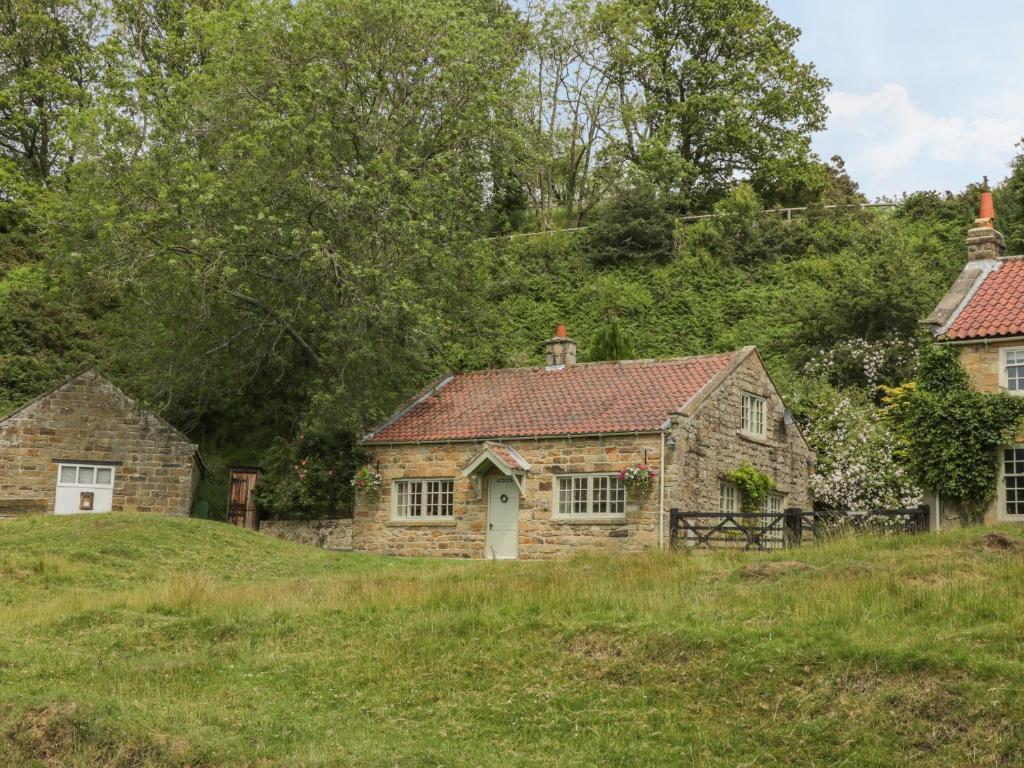 uma velha casa de pedra num campo relvado em Quoits Cottage em Beck Hole