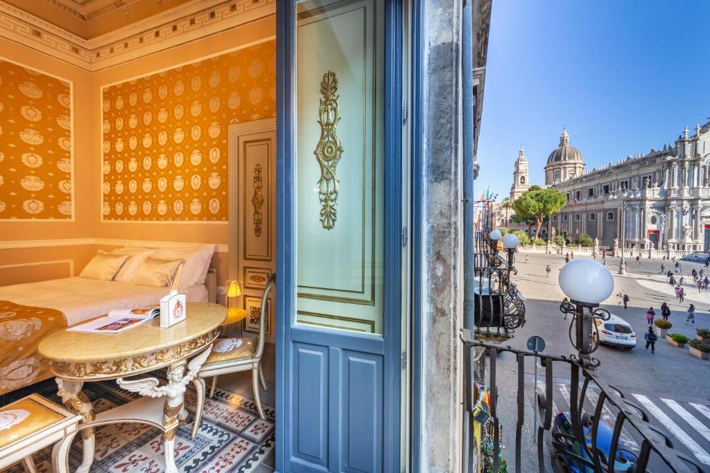 a balcony with a bed and a table and a street at Palazzo Marletta Luxury House Hotel in Catania