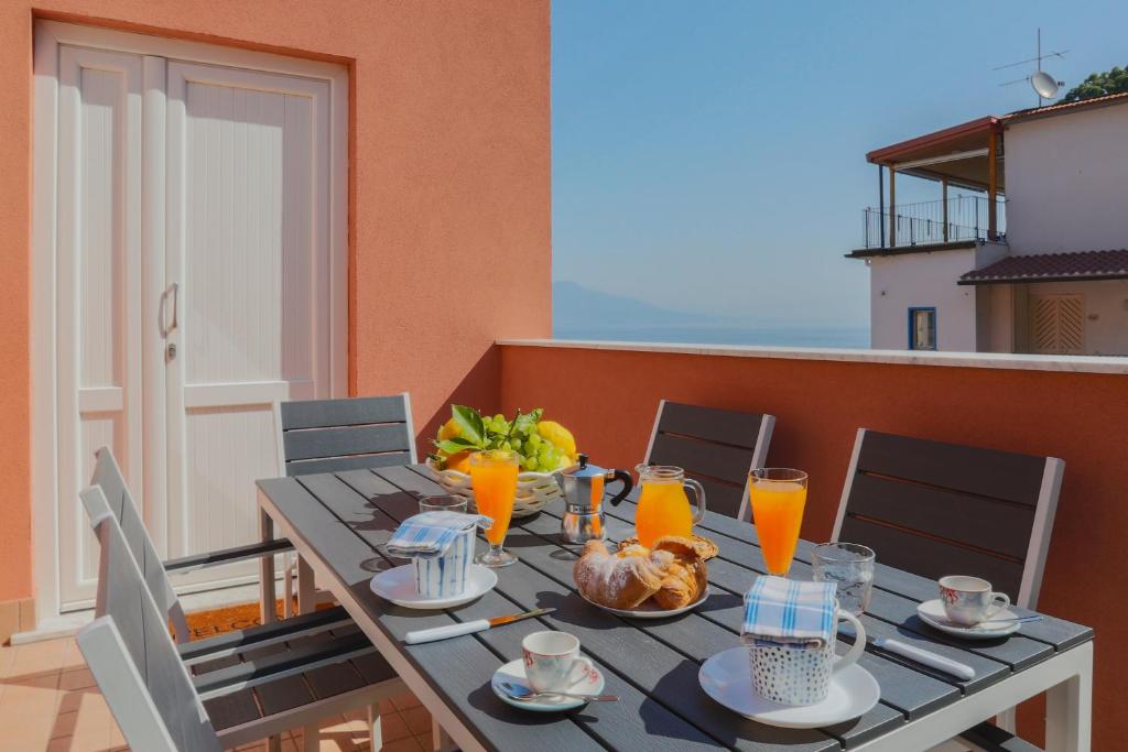 stół z jedzeniem i sokiem pomarańczowym na balkonie w obiekcie SeaView Sorrento Apartment by the sea with terrace w Sorrento