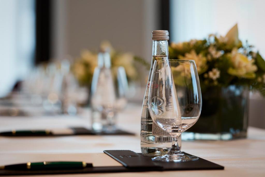 a bottle of water sitting on a table with a wine glass at The Reverie Saigon in Ho Chi Minh City