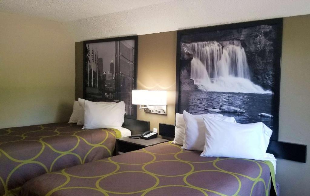 a hotel room with two beds and a painting on the wall at Super 8 by Wyndham Brownsburg in Brownsburg