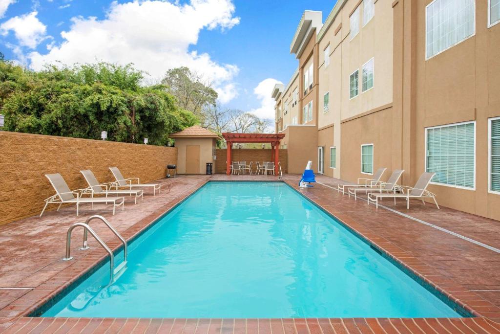 a swimming pool with chairs and a building at La Quinta by Wyndham Lake Charles - Westlake in Westlake