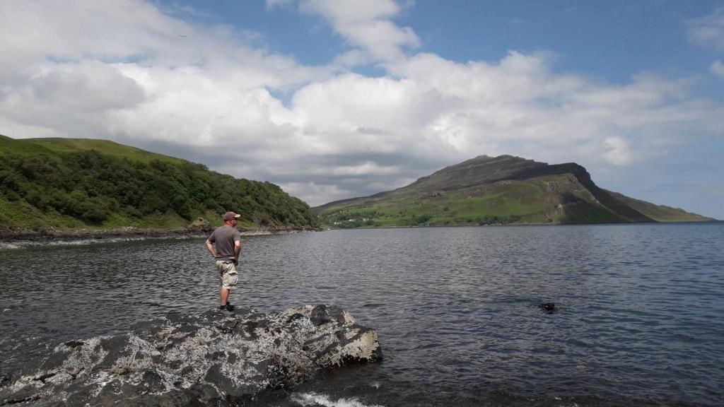 a man standing on a rock in a body of water at Balmoral Skye in Portree