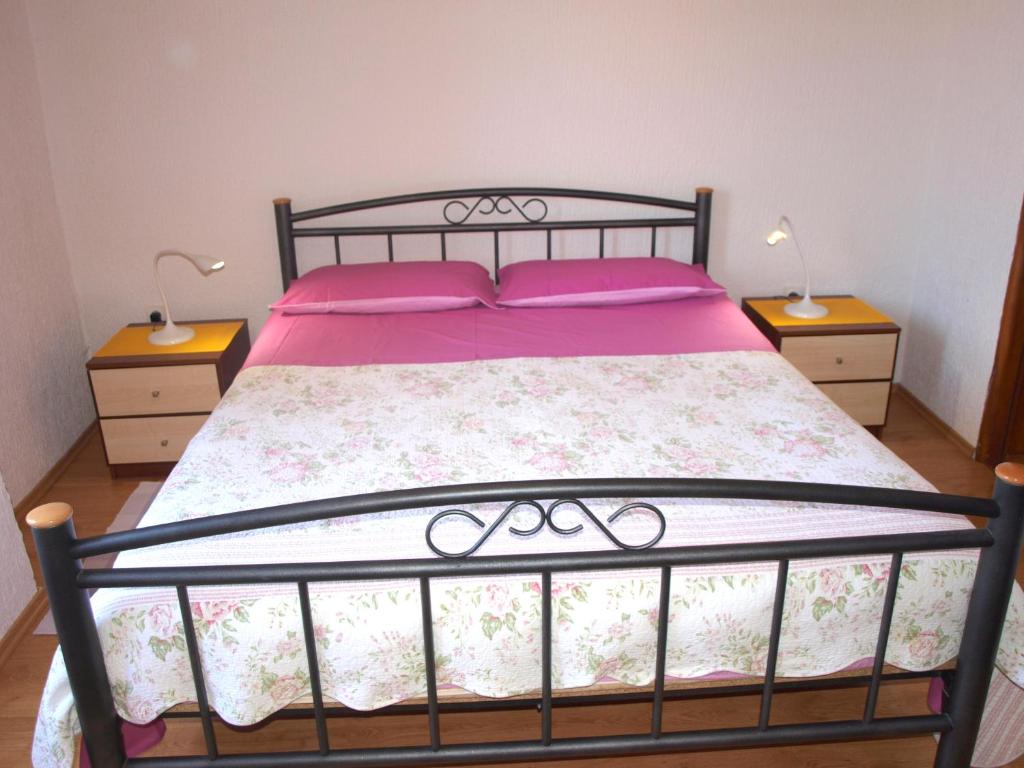 ein Schlafzimmer mit einem Bett mit rosa Bettwäsche und zwei Nachttischen in der Unterkunft Apartment 52 in Rovinj