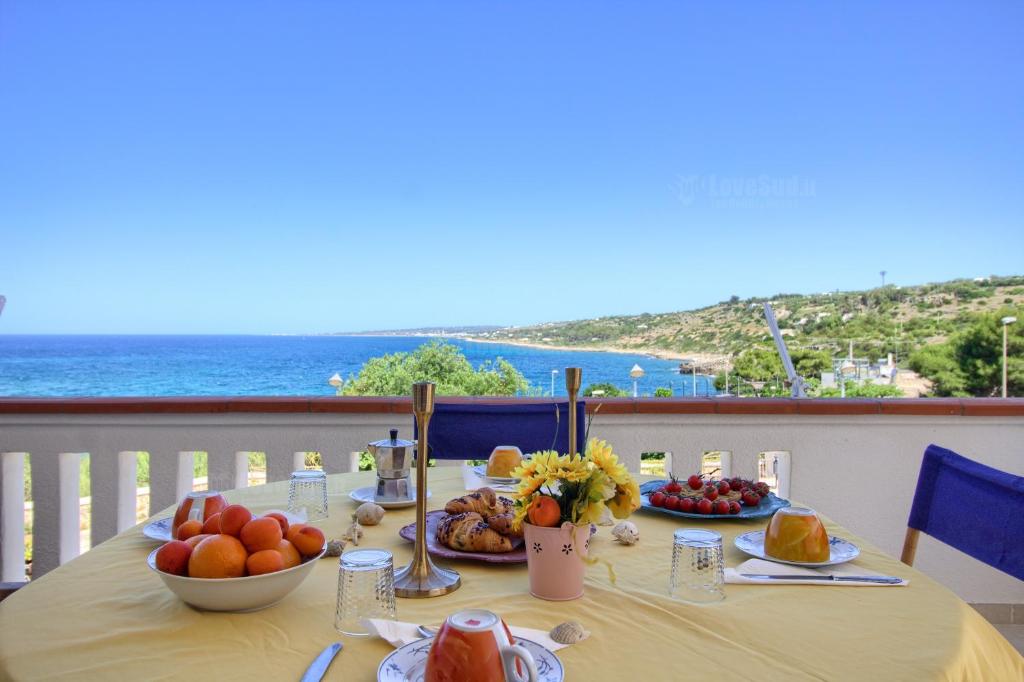 een tafel met eten erop met uitzicht op de oceaan bij SUNSET GREG - fronte mare San Gregorio by LoveSud in Leuca