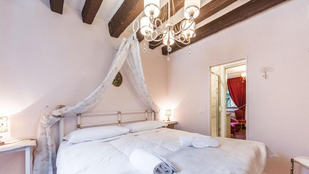 um quarto com uma cama branca e um lustre em Residenza La Salute em Veneza