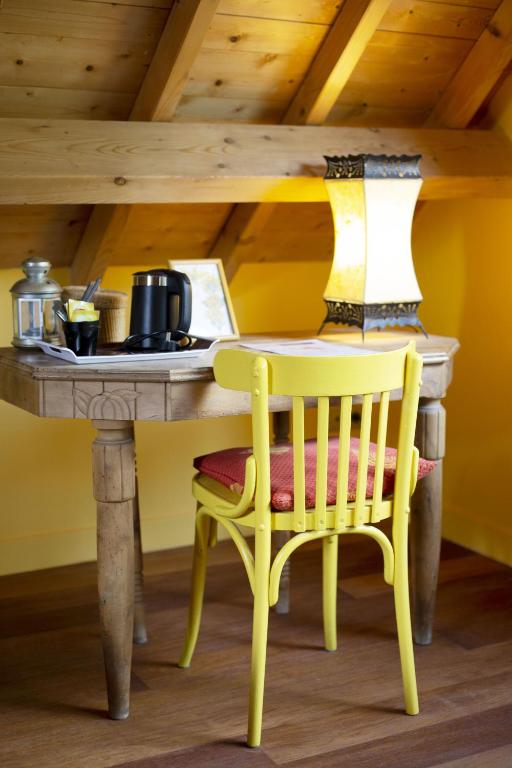 a table with a yellow chair and a table with a laptop at Les gerbes in Arras-en-Lavedan