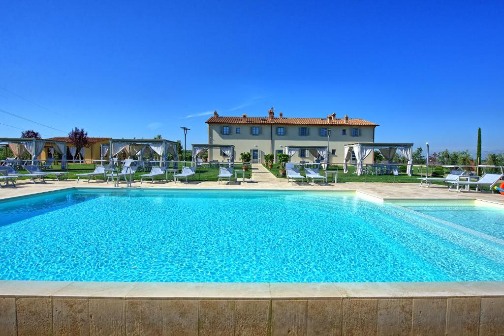 una piscina con sedie e una casa sullo sfondo di Il Sole di Vino by PosarelliVillas a Vinci