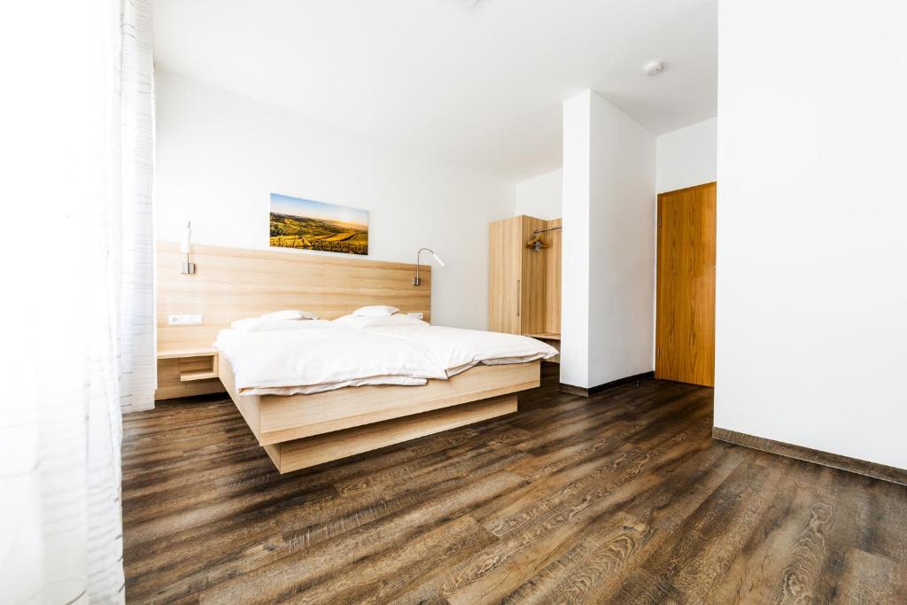 1 dormitorio con paredes blancas, suelo de madera y 1 cama en Hotel zur Post, en Heilbronn