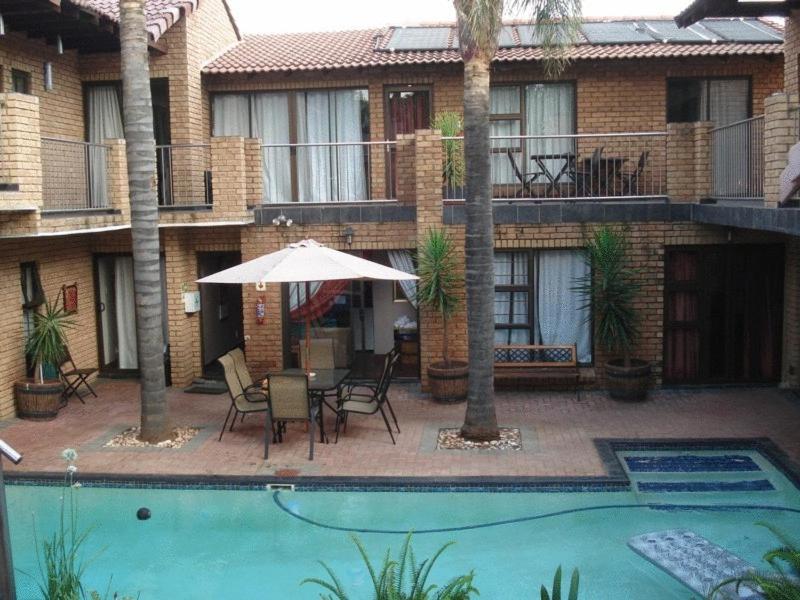 a patio with a table and chairs and an umbrella at Uitsigpark Guest@home4U in Centurion