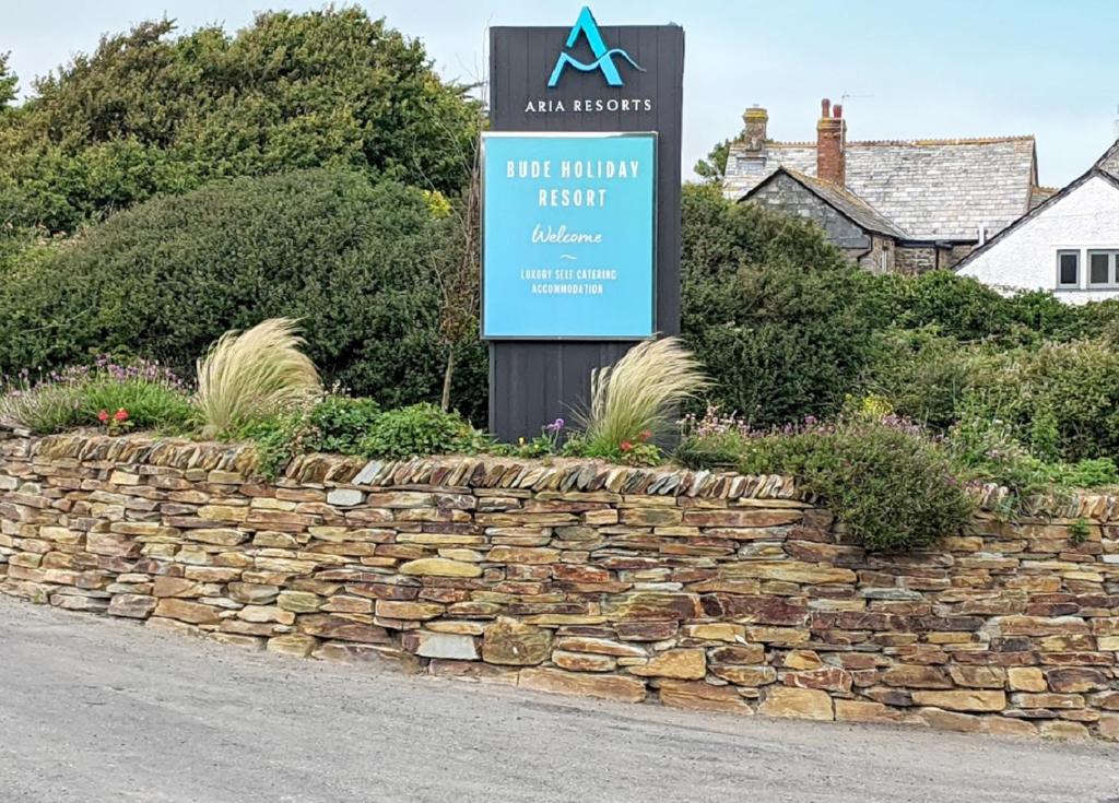 a sign in a stone wall next to a street at Bude Holiday Resort in Bude