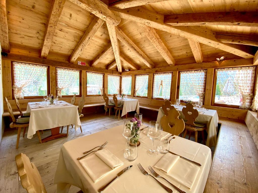 uma sala de jantar com mesas, cadeiras e janelas em Ristorante Rifugio Ospitale em Cortina dʼAmpezzo