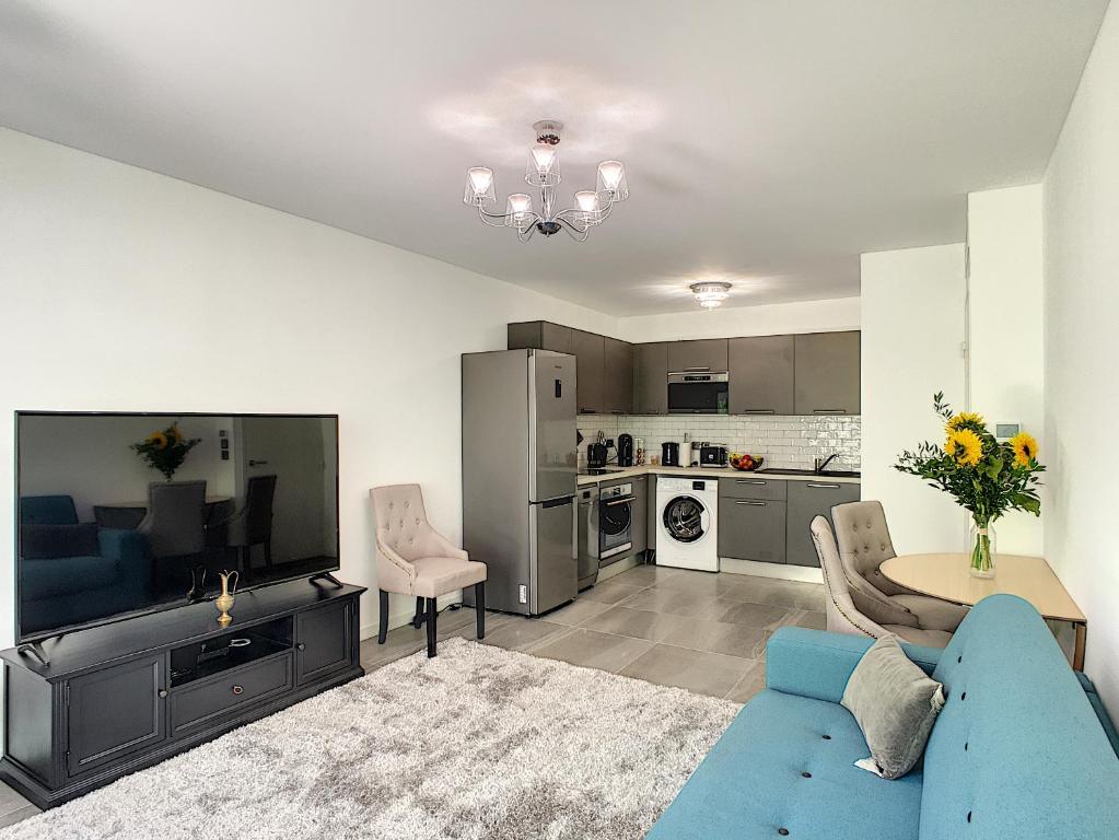 un salon avec un canapé bleu et une cuisine dans l'établissement Palm Beach apartment with a pool in the residence, à Cannes