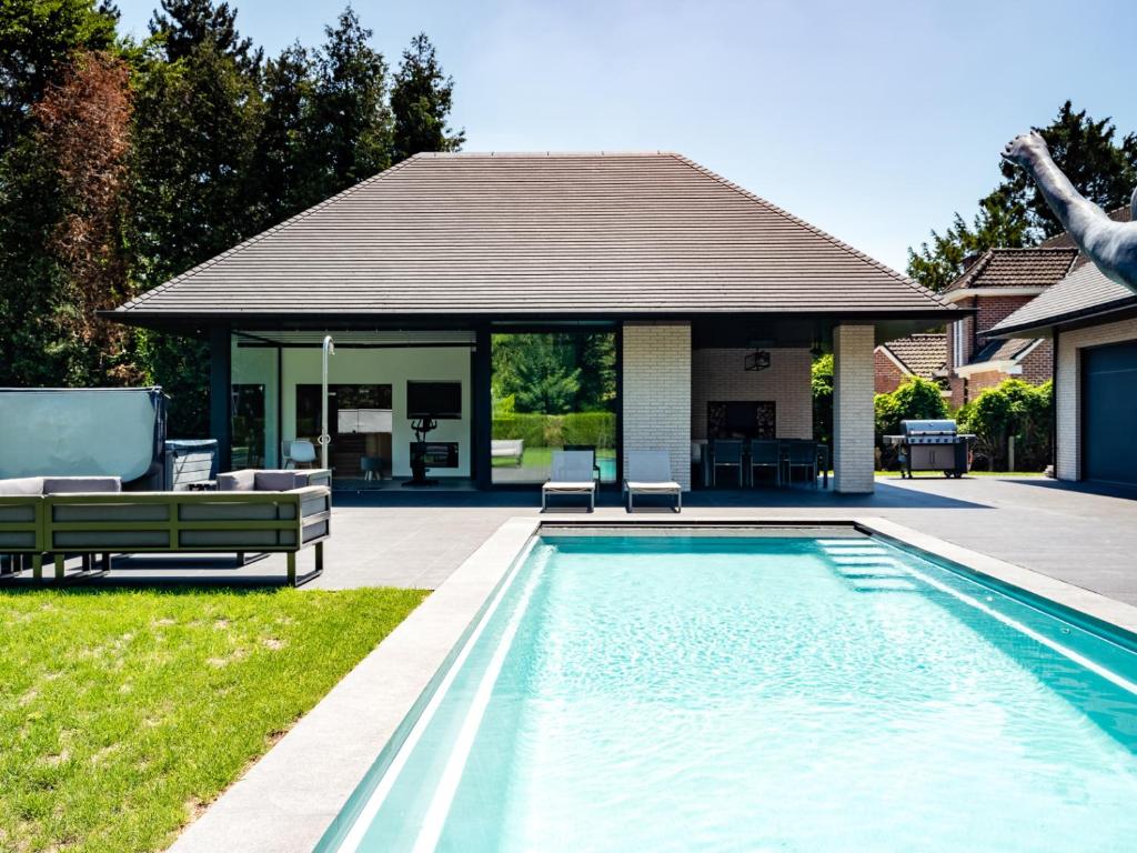 a swimming pool in front of a house at B&B Welness Sport and Pleasure in Laarne