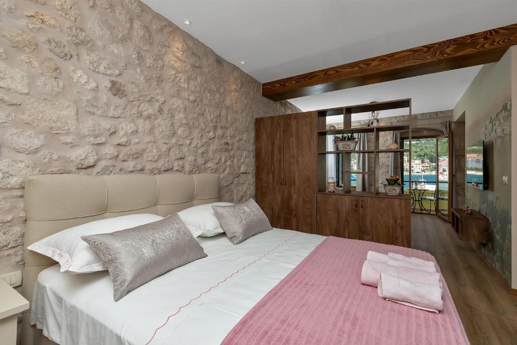 a bedroom with a large bed with a stone wall at Lux Dado Igrane in Igrane