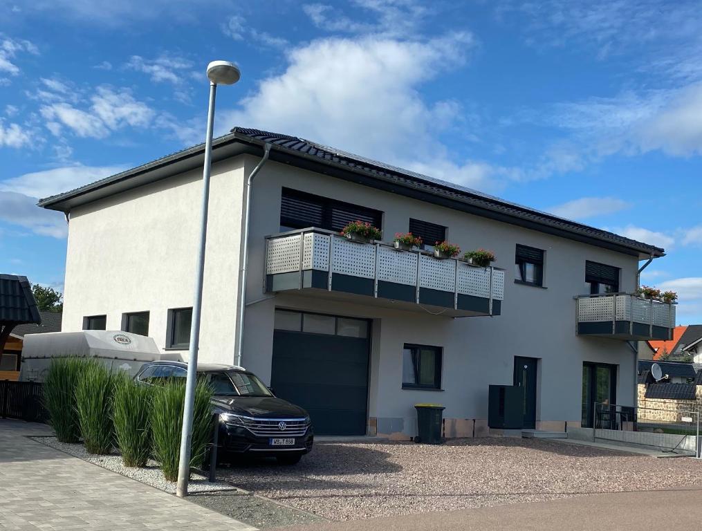 uma casa branca com um carro estacionado em frente dela em Ferienwohnung zur Dexter-Zucht Coswig (Anhalt) em Coswig