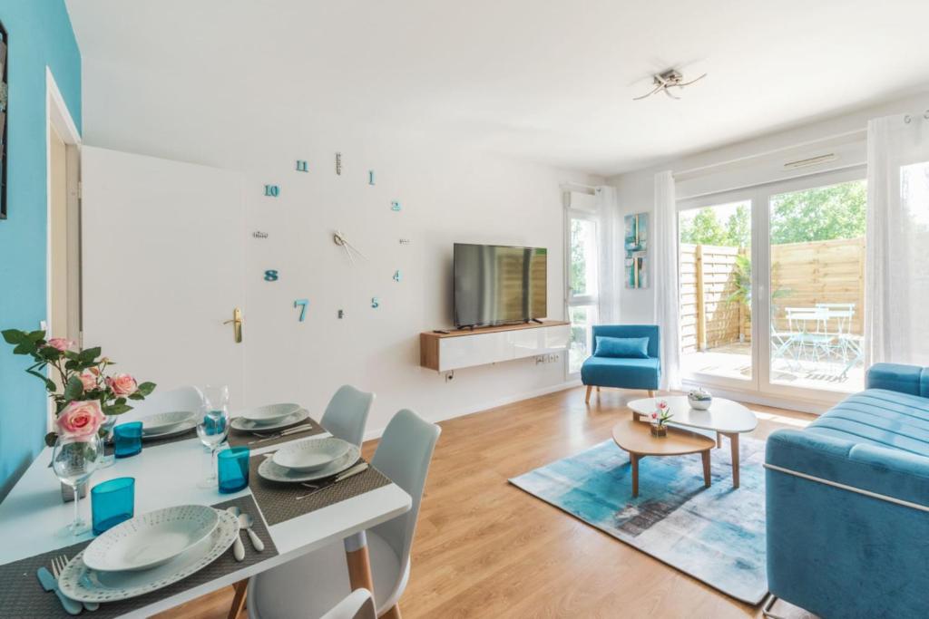 un salon avec une table et un canapé bleu dans l'établissement Appartement des Rêves Bleus - Welkeys, à Montévrain