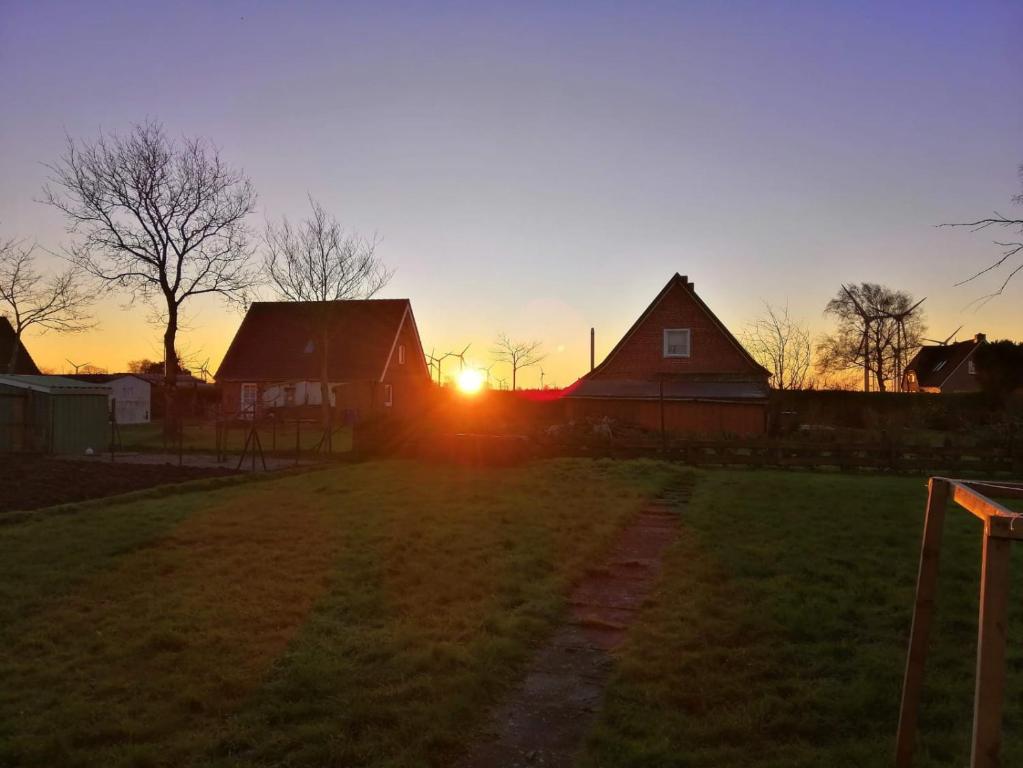 a sunset over a field with two barns at Ferienhaus Krabbenloch Friedrichskoog in Friedrichskoog