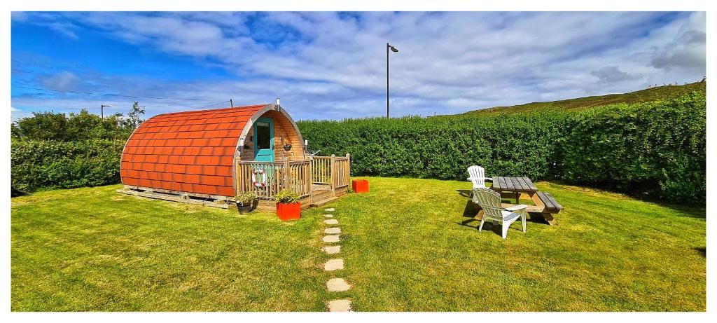 an orange dome house in a yard with a table and chairs at Spinning Wheel Pod in Dunvegan