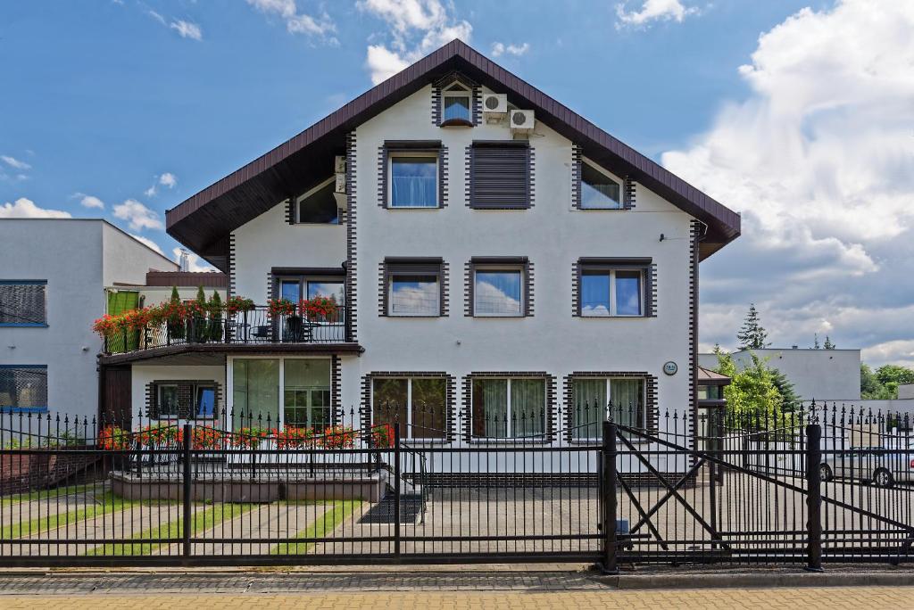 a white house with a black fence at Pensjon Polska in Poznań