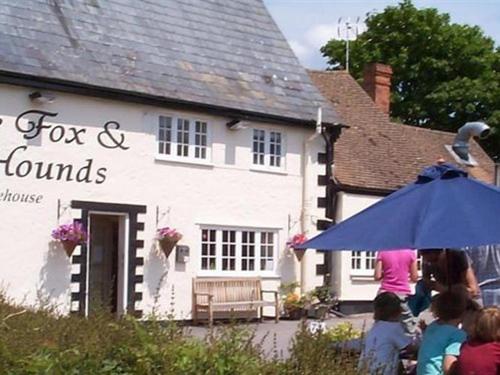 un grupo de personas de pie fuera de una casa con un paraguas en The Fox & Hounds, en Faringdon