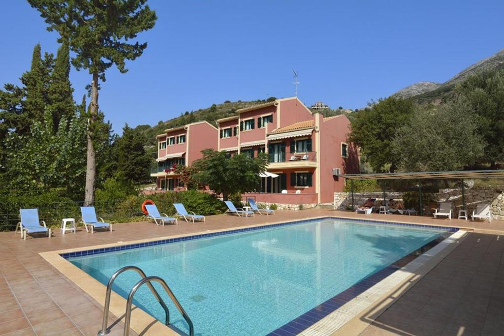 a large swimming pool with chairs and a building at Vivi's Apartments in Ayia Evfimia