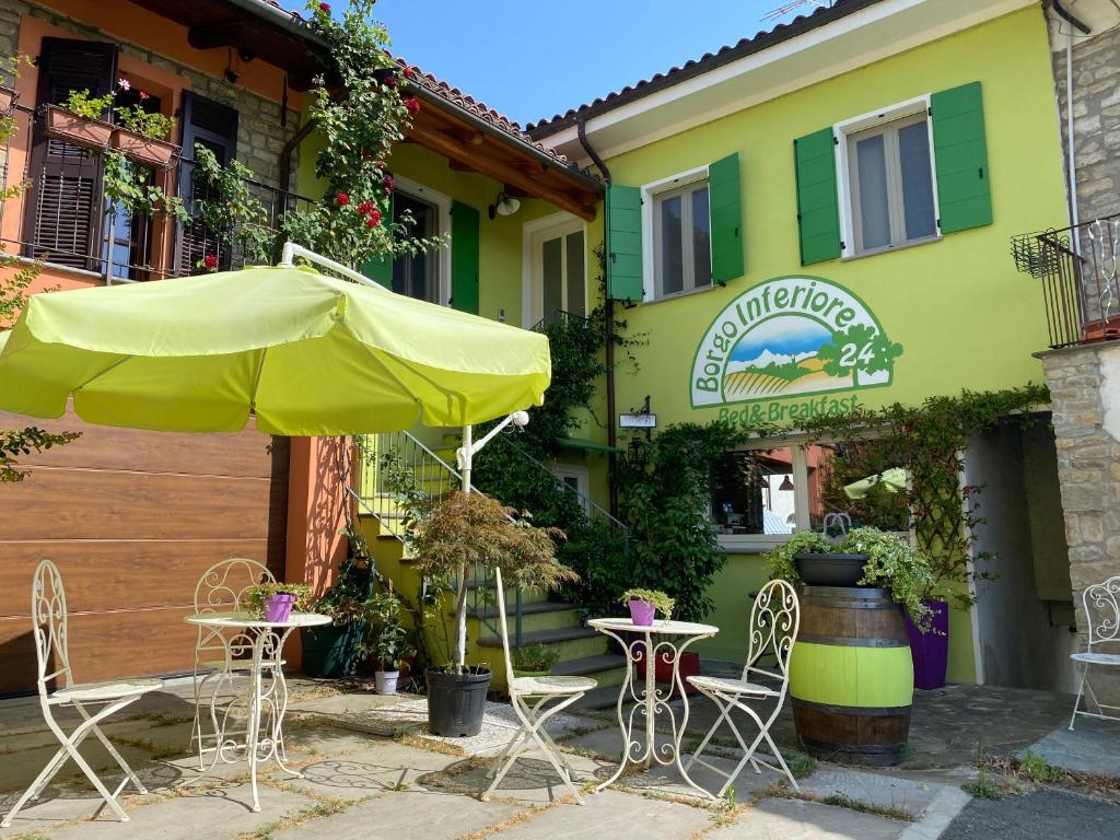 a yellow building with a table and chairs and an umbrella at Borgo Inferiore 24 in Acqui Terme