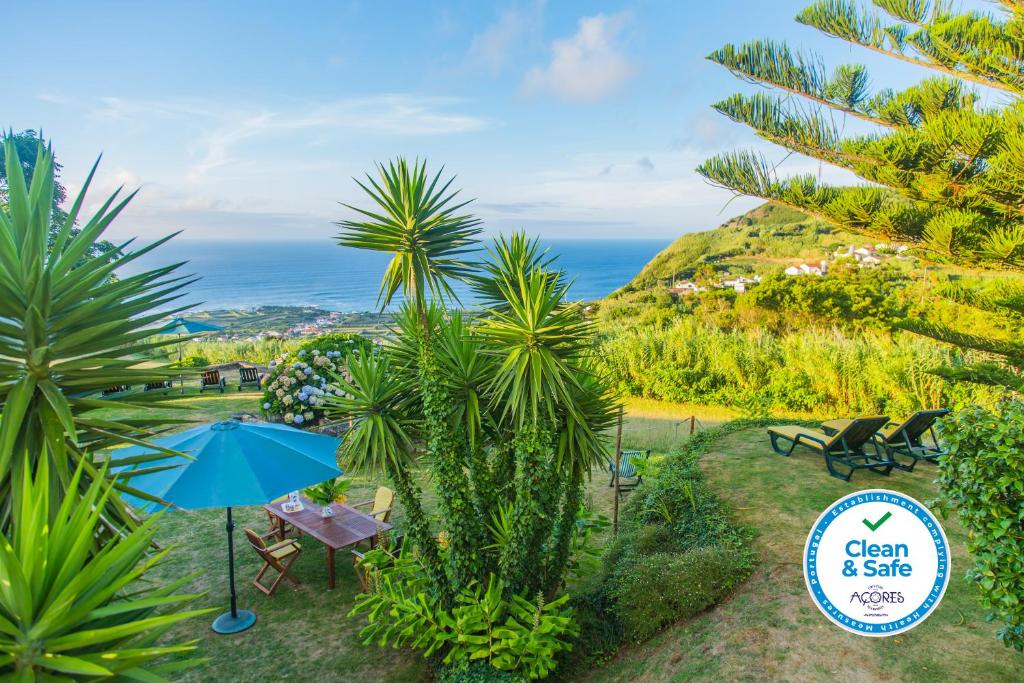 a garden with a table and an umbrella and the ocean at Casa de Pilatos in Mosteiros