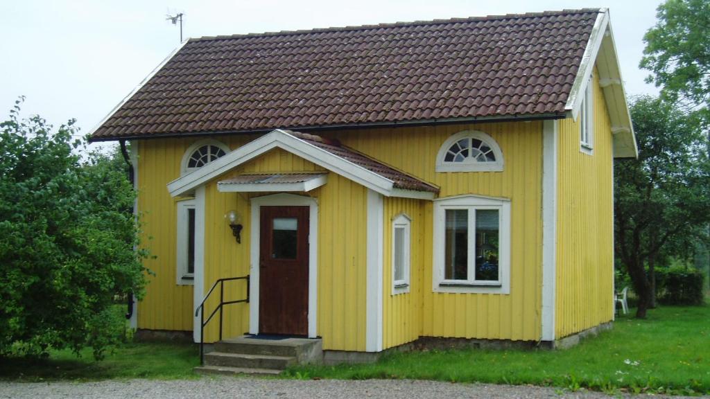 una casita amarilla con una puerta roja en Vegby Bolsgård "Lillstugan", en Moheda