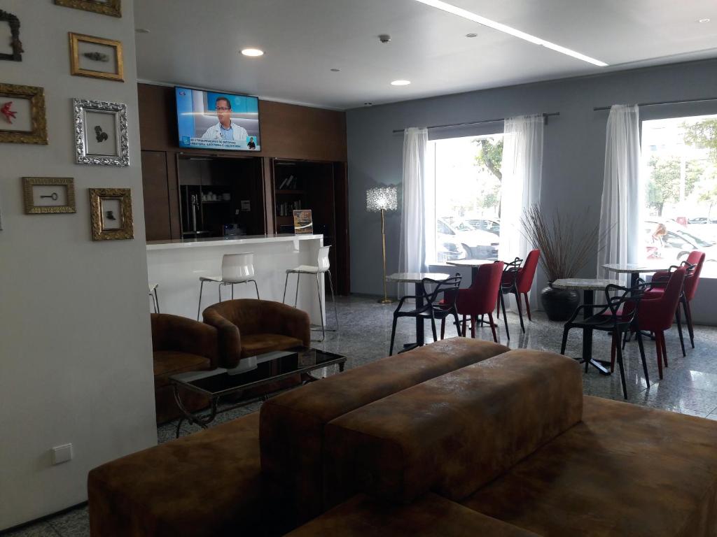 A hotel lounge with leather seating, café tables, a television, and large windows.