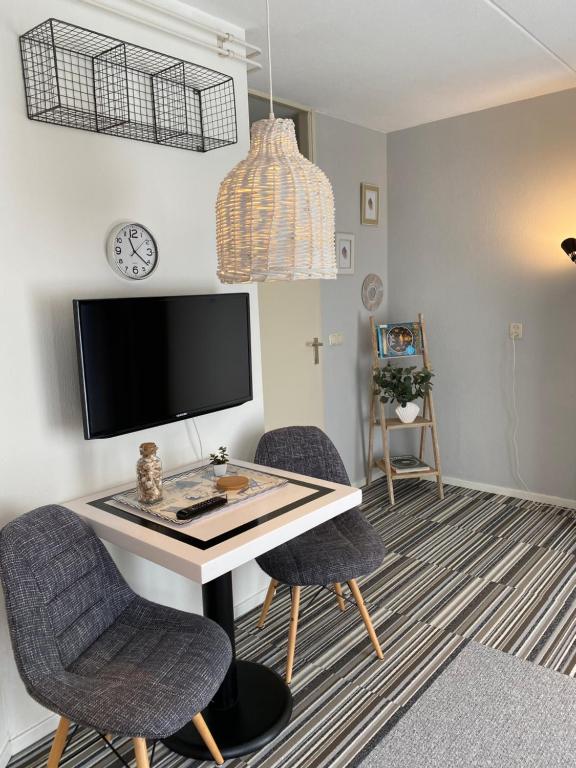 een kamer met een bureau met 2 stoelen en een televisie bij Texelheerlijk 10 in De Koog