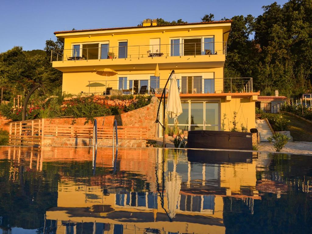a yellow house with a boat in the water at Villa Annika in Lovran