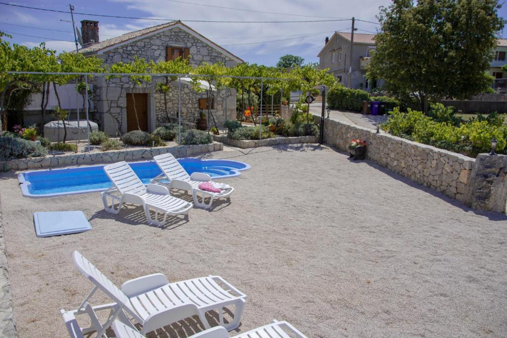 a patio with chairs and a table and a pool at Traditional Stone House St.Anton in Malinska