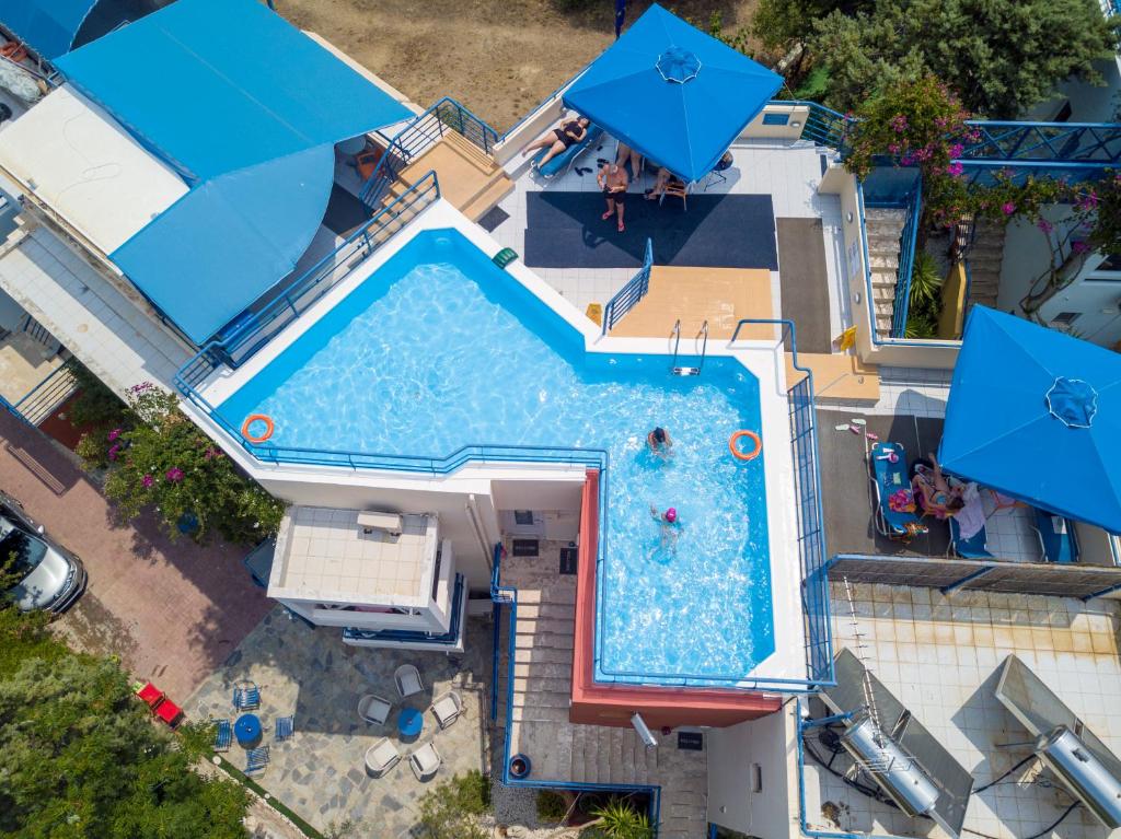 an overhead view of a swimming pool with blue umbrellas at Heliotopos Apartments in Tolo