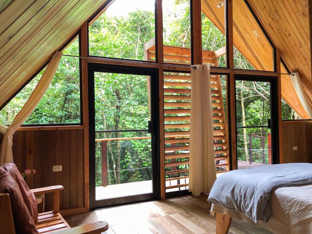 1 dormitorio en una casa del árbol con ventanas grandes en Tityra Lodge en Monteverde