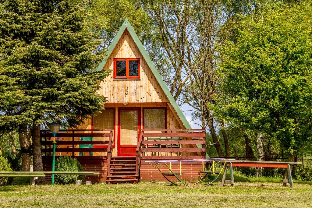 una pequeña casa con una puerta roja en el bosque en The Rainbow - Domki Letniskowe, en Dźwirzyno