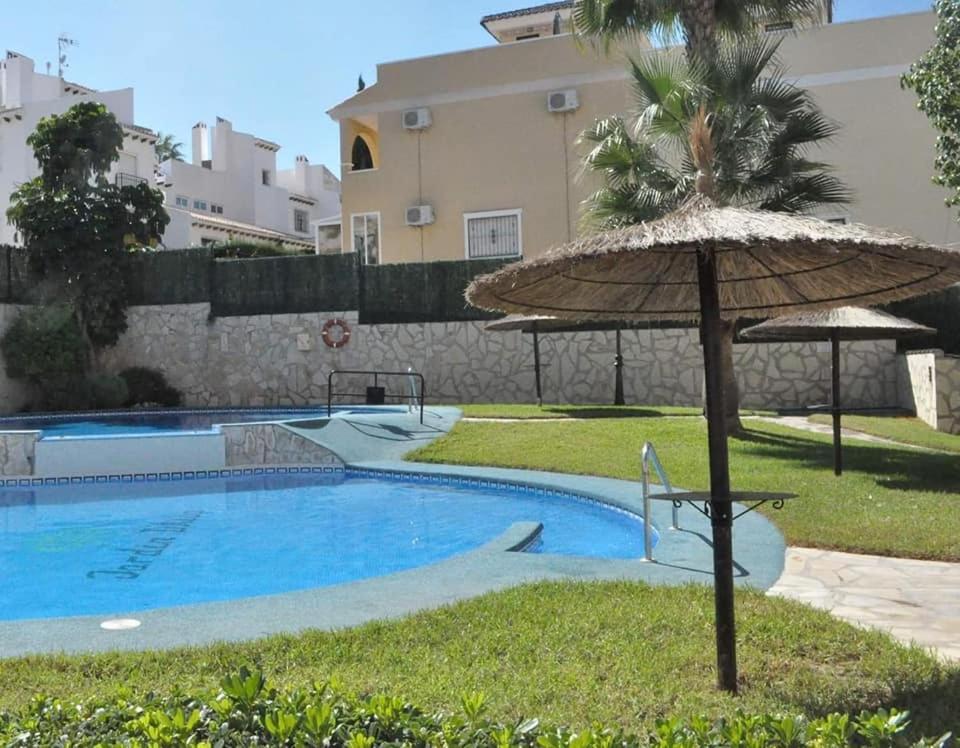 uma piscina com um guarda-sol, uma mesa e uma cadeira em Apartament Jardin De Alba in Villamartin em Orihuela