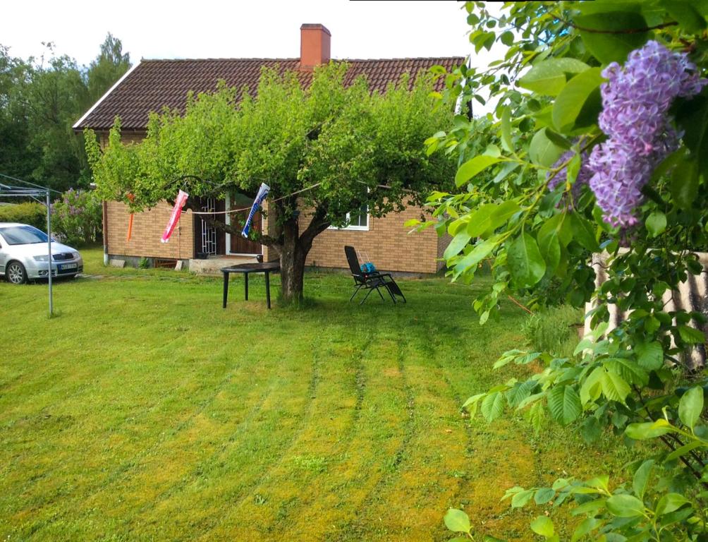 a yard with a tree and a bench and a house at The Cozy Little House in Motala