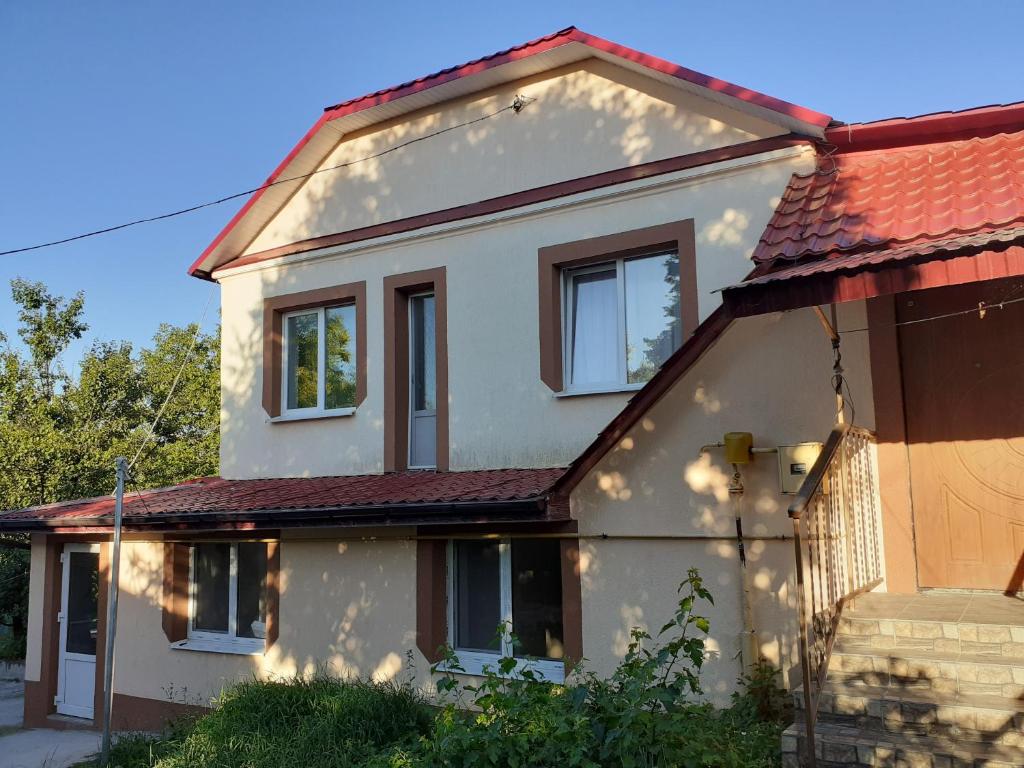 uma casa branca com um telhado vermelho em Татьянин двор em Kamianets-Podilskyi