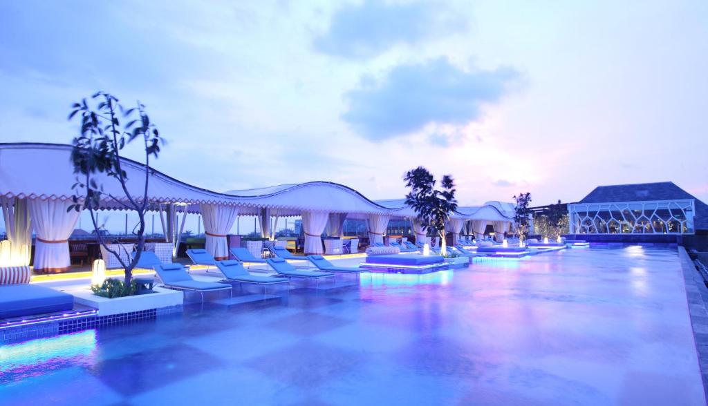 - une piscine avec des chaises longues et un complexe dans l'établissement TS SUITES Seminyak Bali, à Legian