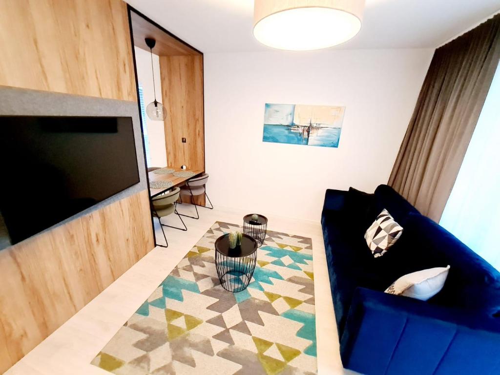 AZURE PREMIUM KOŁOBRZEG في كولوبرزيغ: غرفة معيشة بها أريكة زرقاء وتلفزيون