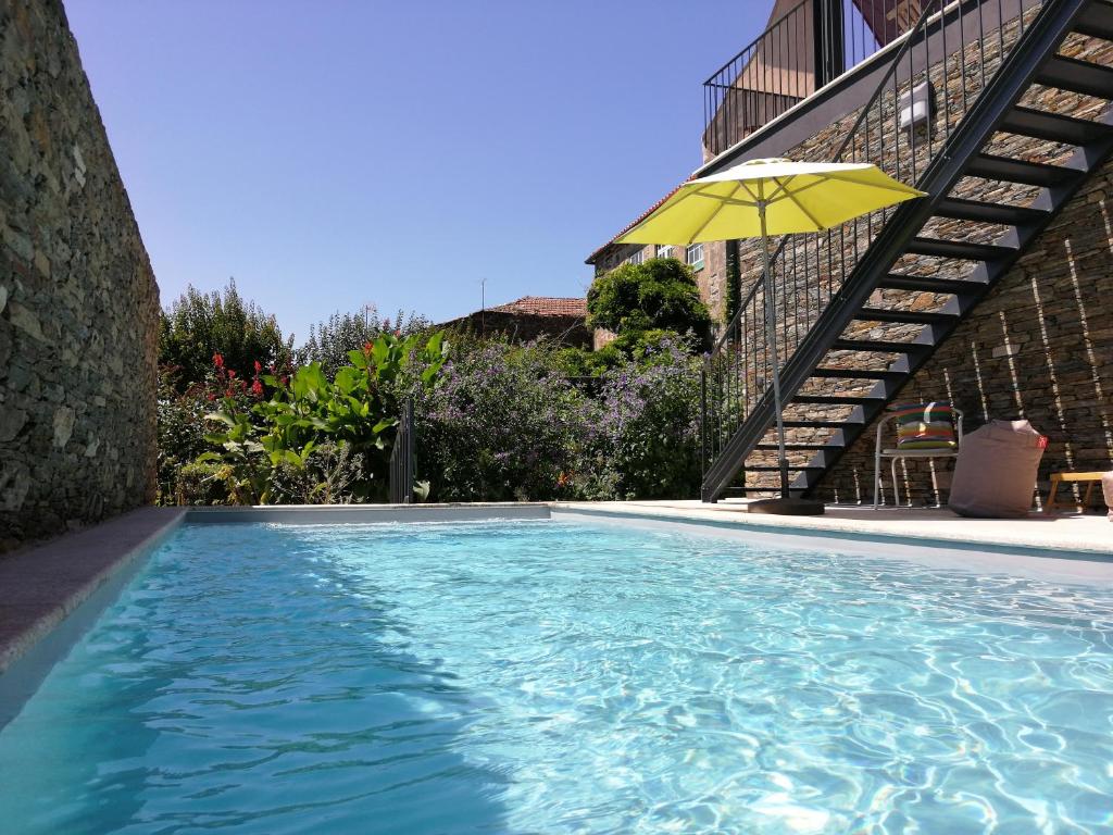 uma grande piscina com um guarda-chuva amarelo em Mesao Provesende em Provesende