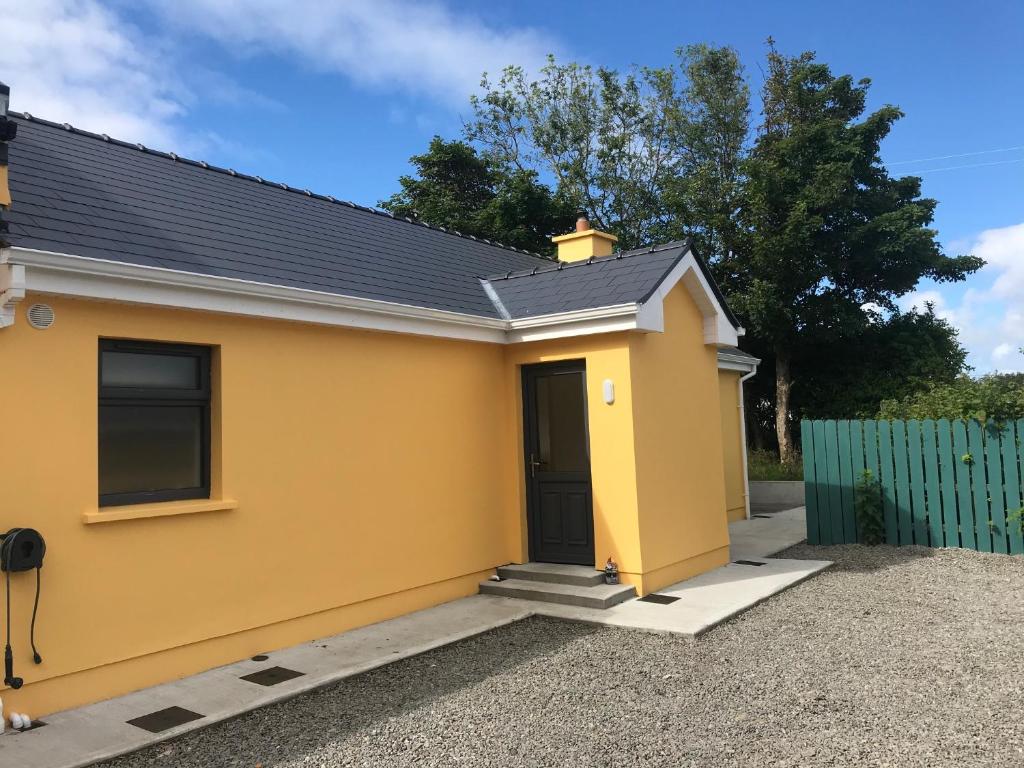 een geel huis met een zwarte deur bij An Nead Beag only 2 miles from Louisburgh in Louisburgh