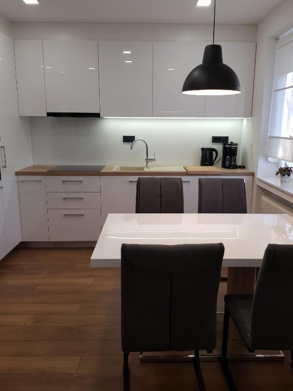 kuchnia z białymi szafkami oraz białym stołem i krzesłami w obiekcie MarSim Lux apartman Zagreb w Zagrzebiu