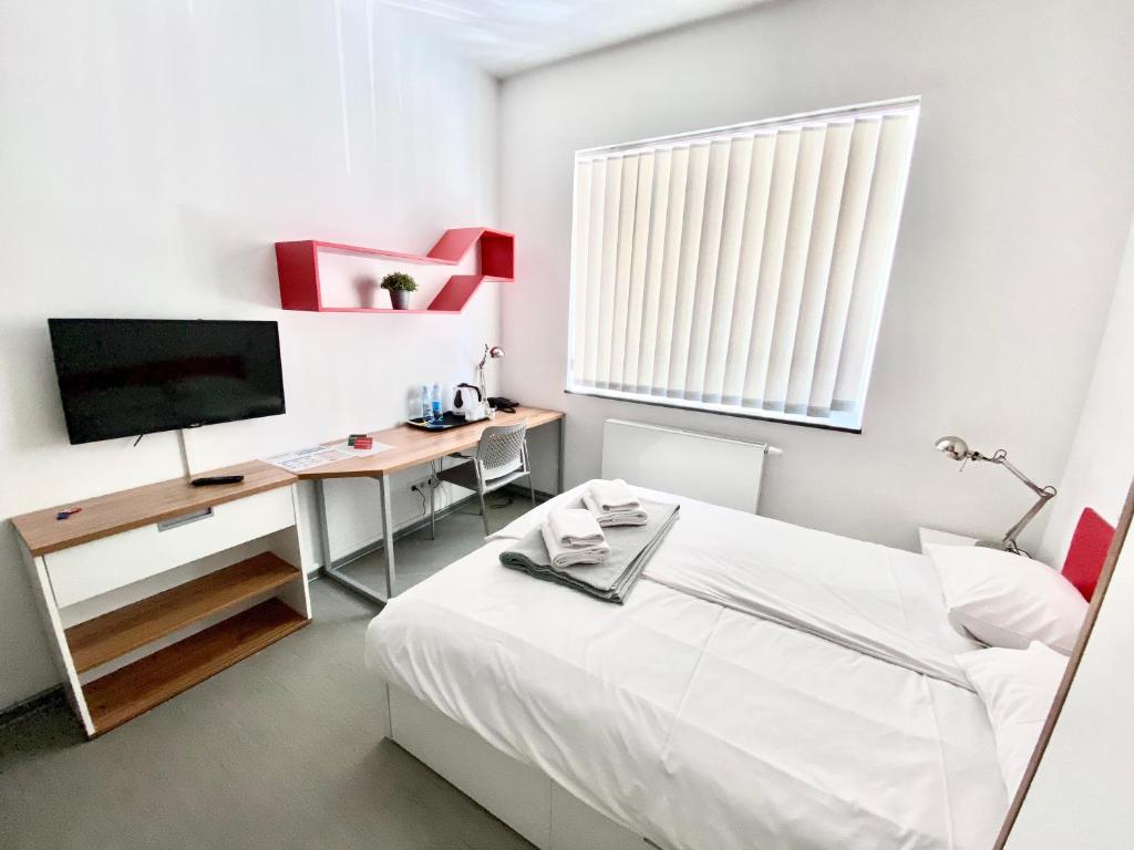 a bedroom with a bed and a desk with a television at Esperanto Home in Katowice